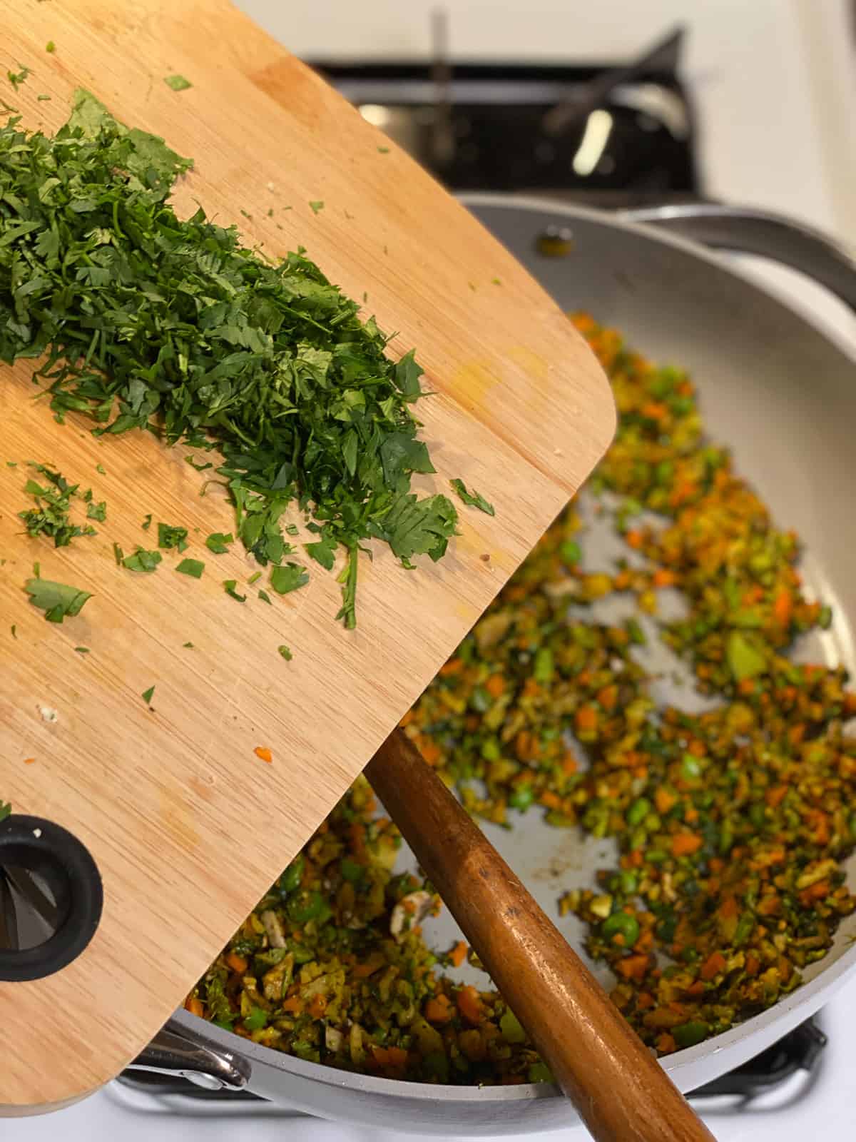 Process shot of adding chopped cilantro to the pan