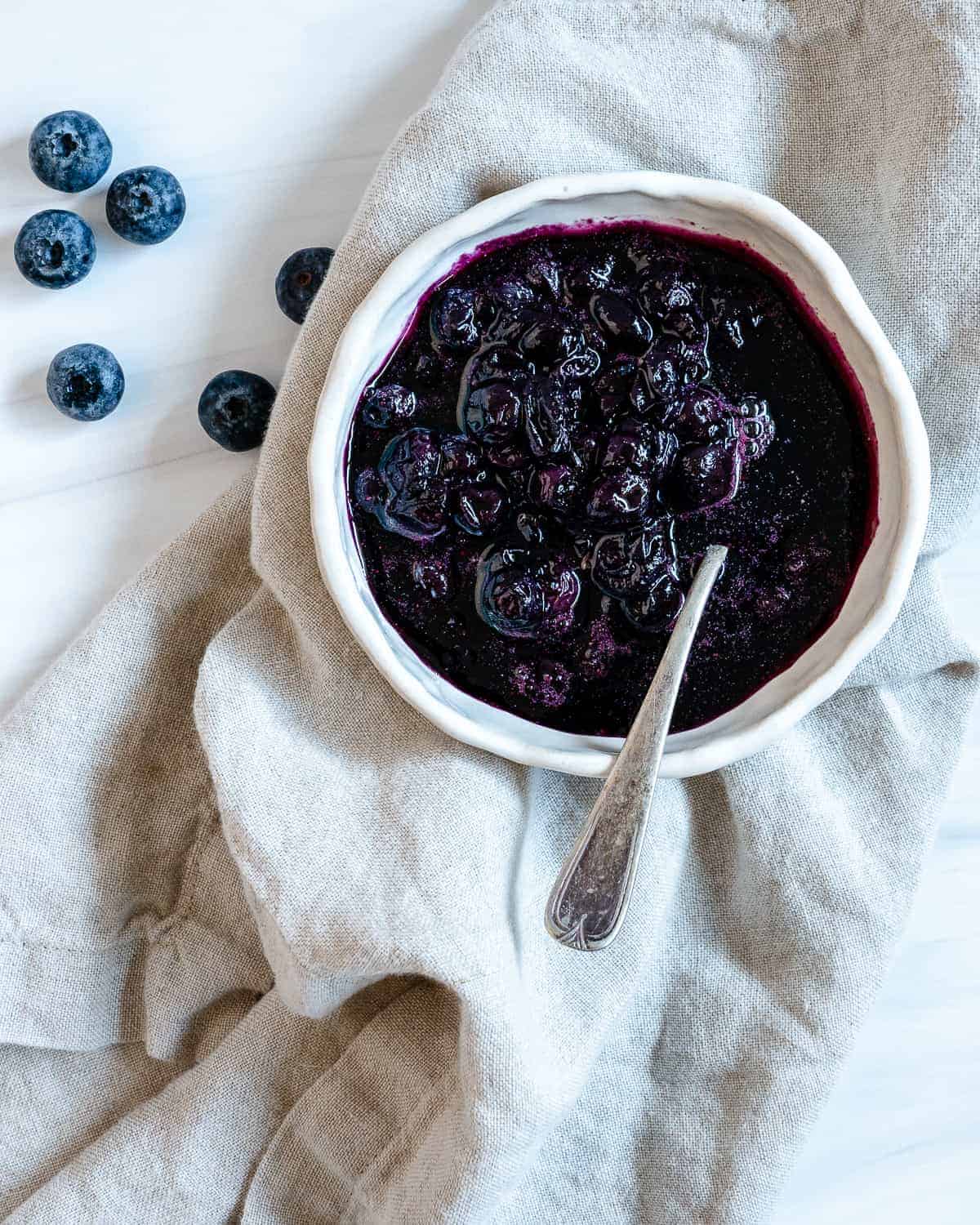 completed 2 Minute Blueberry Maple Syrup in a white bowl against a white surface and light towel