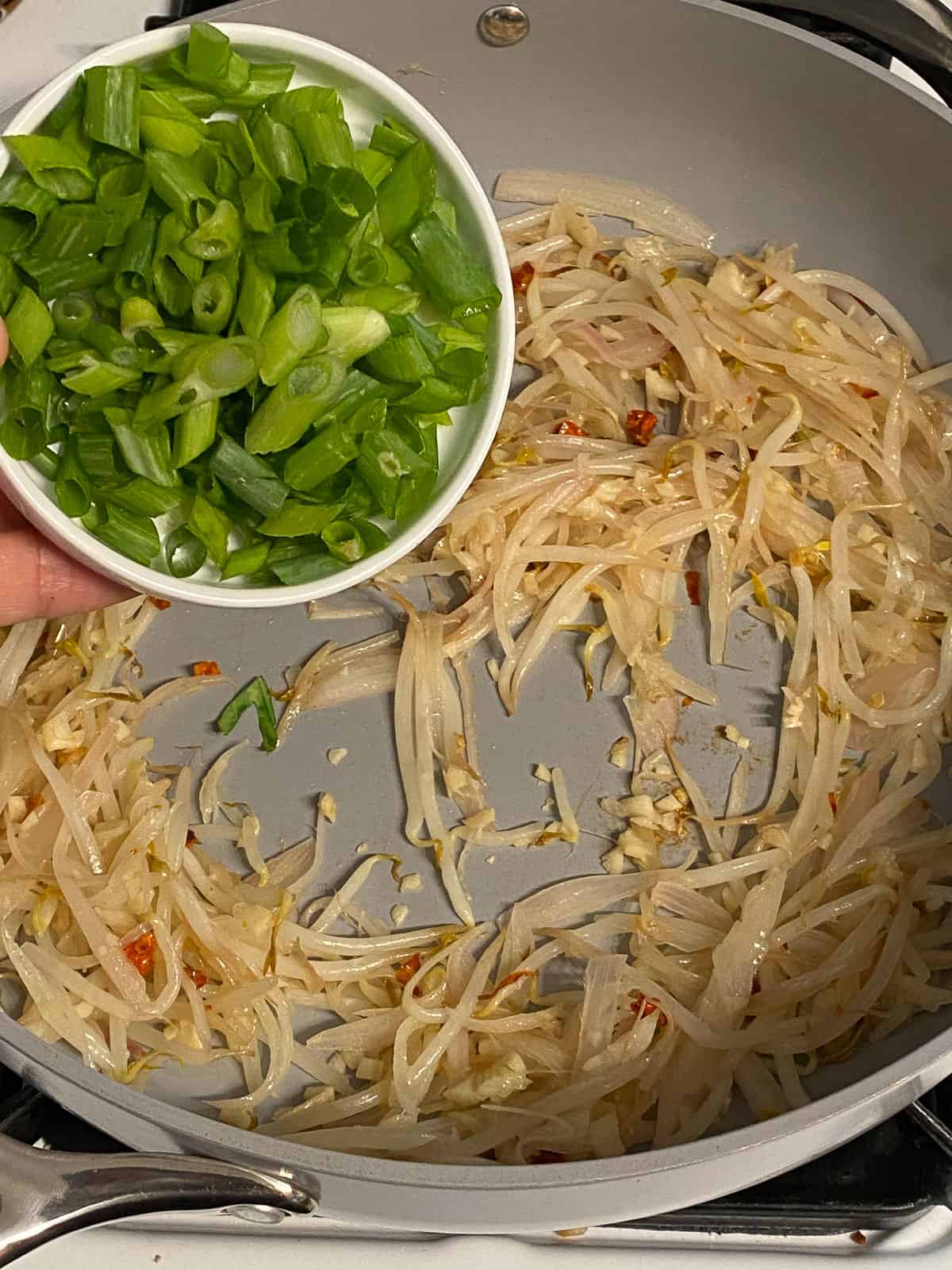 process of adding green onions to pan