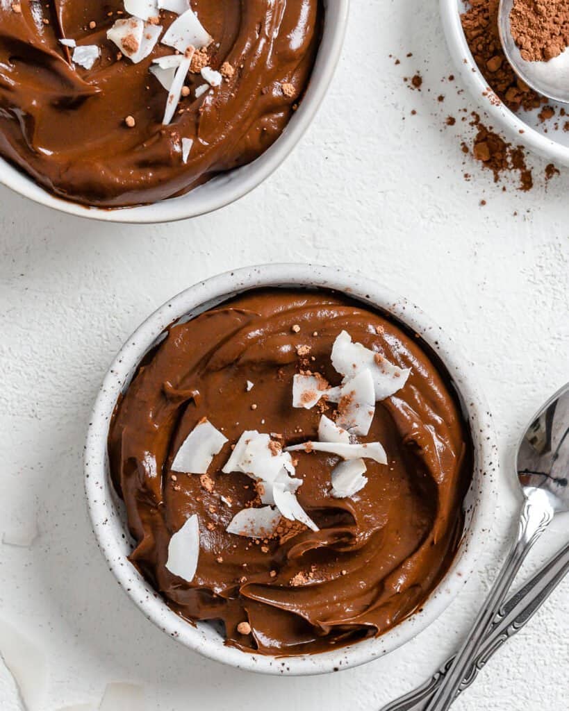 completed chocolate avocado pudding in two white bowls against a white background