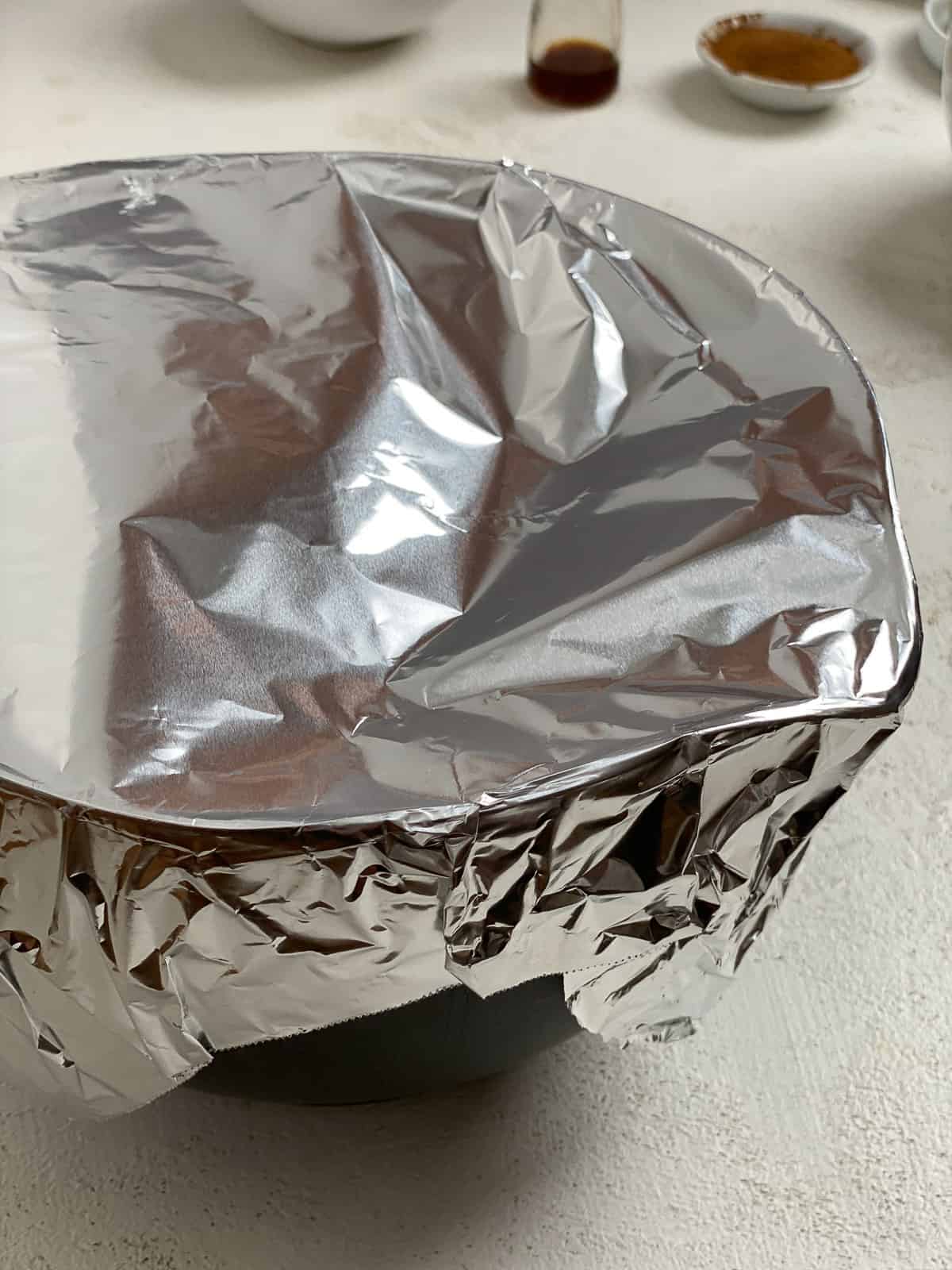 ball of dough in a bowl with foil on top