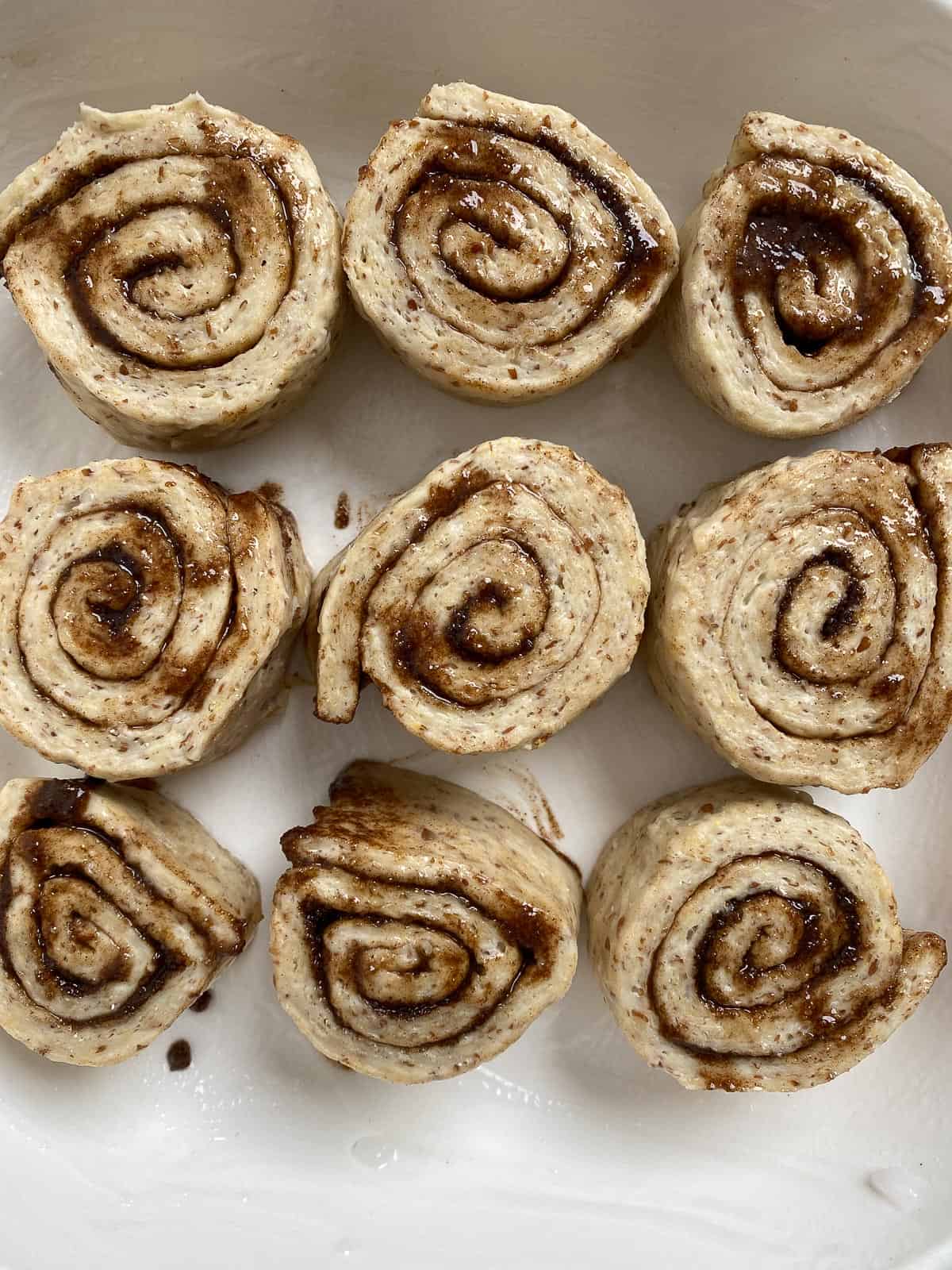 rolled up cinnamon dough pieces on a white surface