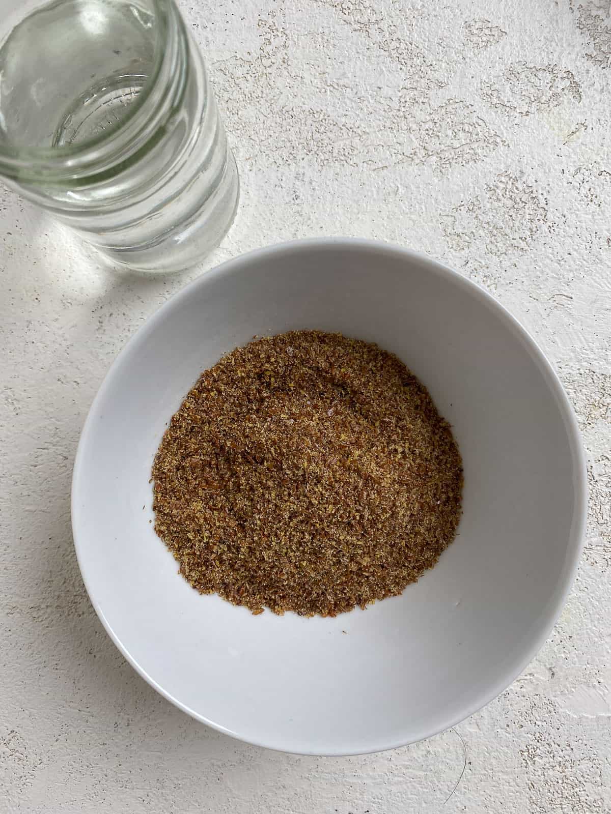 flaxseed in a bowl alongside a bowl of water