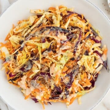 completed coleslaw in a white bowl against a white surface