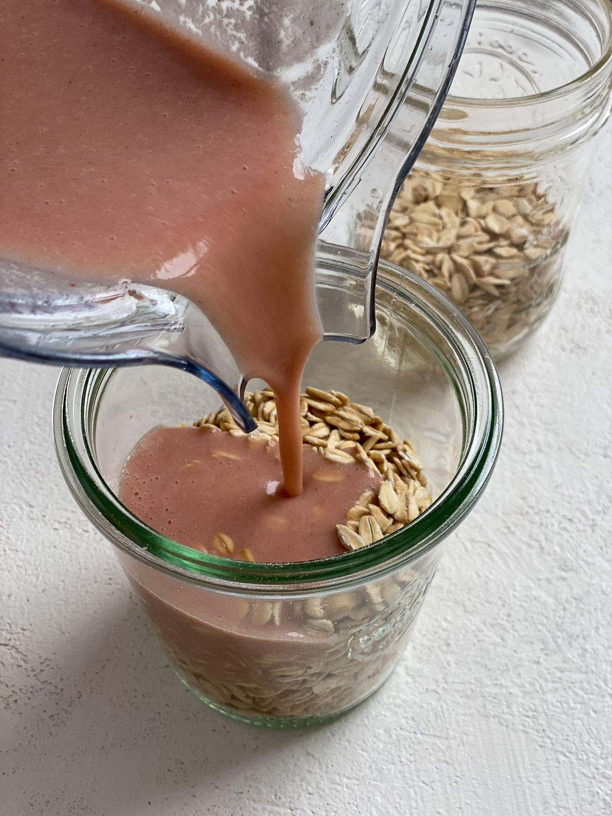 process of mixture being added to glass jar of oats