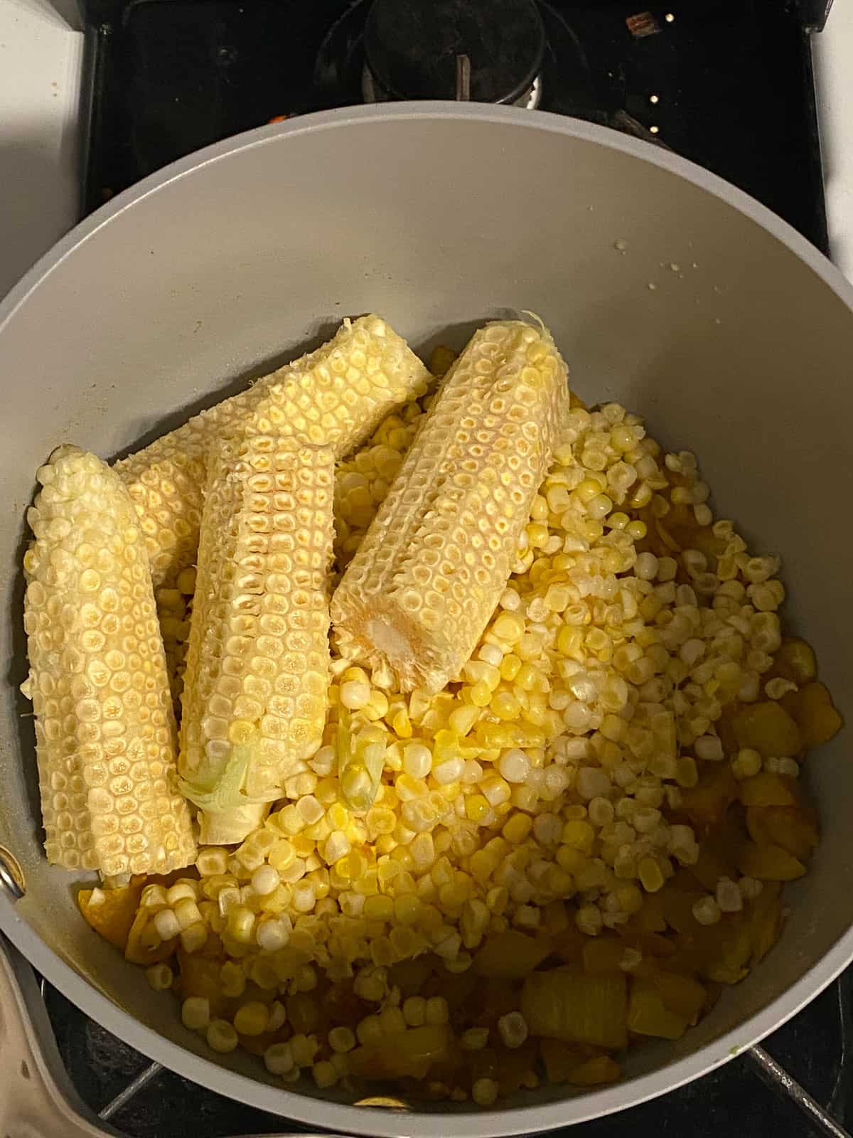 process shot of adding cobbs of corn to pan