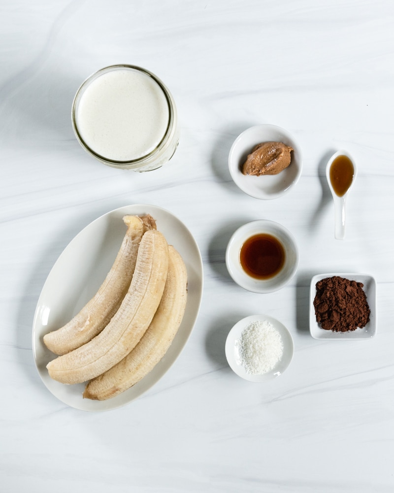 συστατικά για Smoothie μπανάνας με φυστικοβούτυρο σοκολάτας σε λευκή επιφάνεια