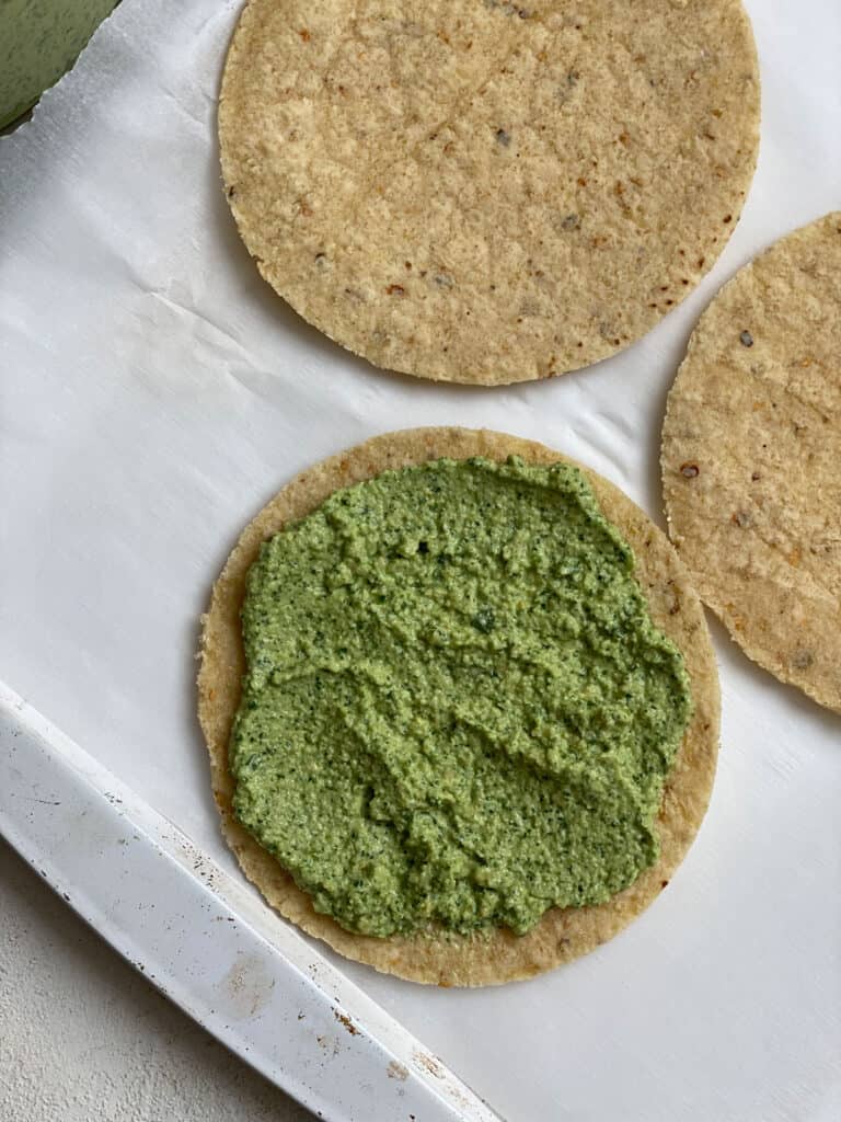 process shot showing the spreading of pesto on one tortilla