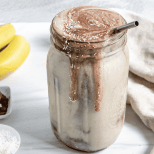 completed Chocolate Peanut Butter Banana Smoothie in a jar with ingredients in the background
