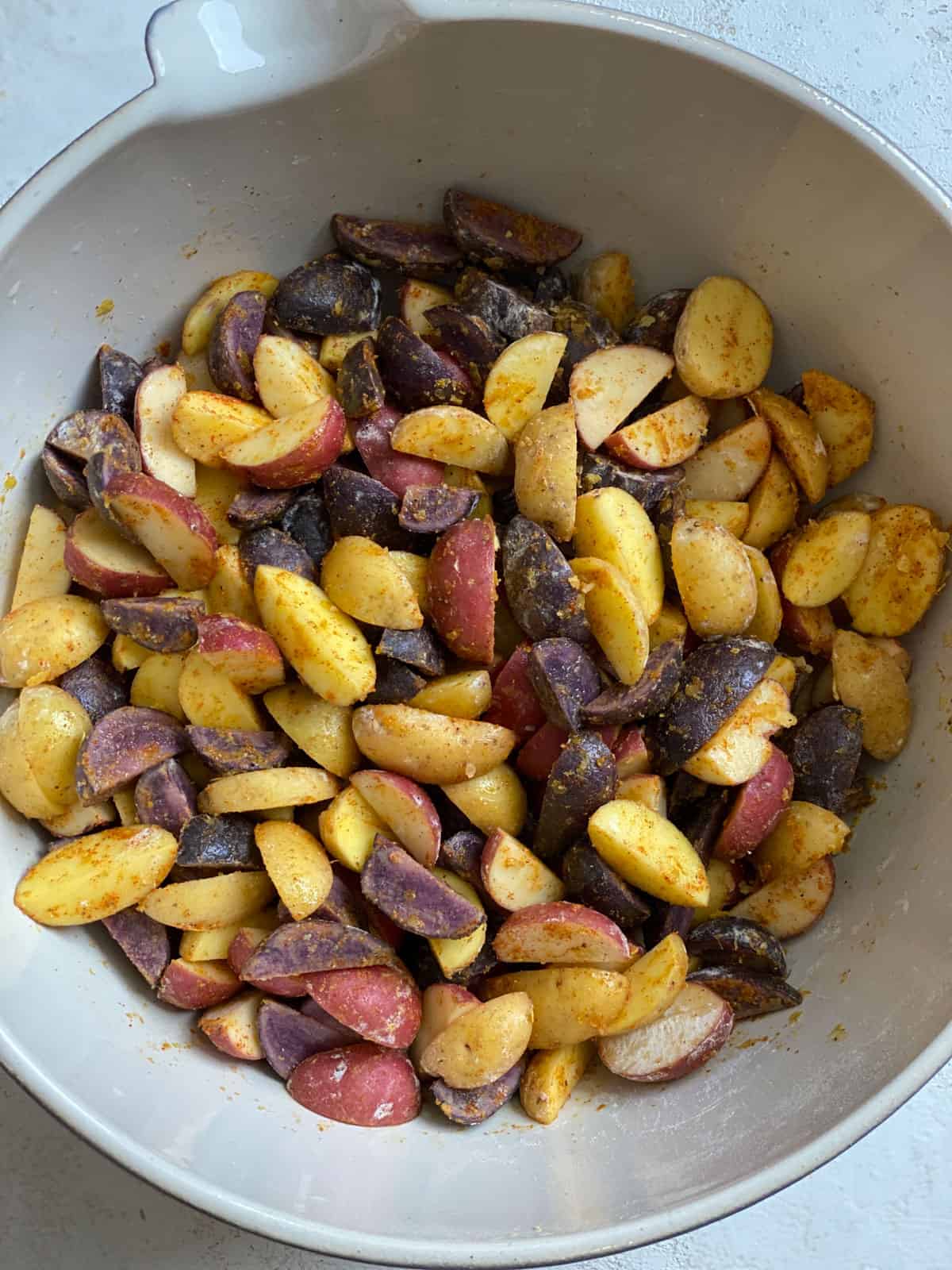 process shot of mixed ingredients for Crispy Purple Potatoes Recipe together in a bowl