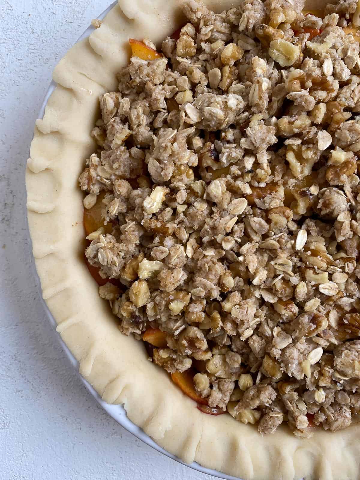 pre-baked peach crumb pie against a white surface