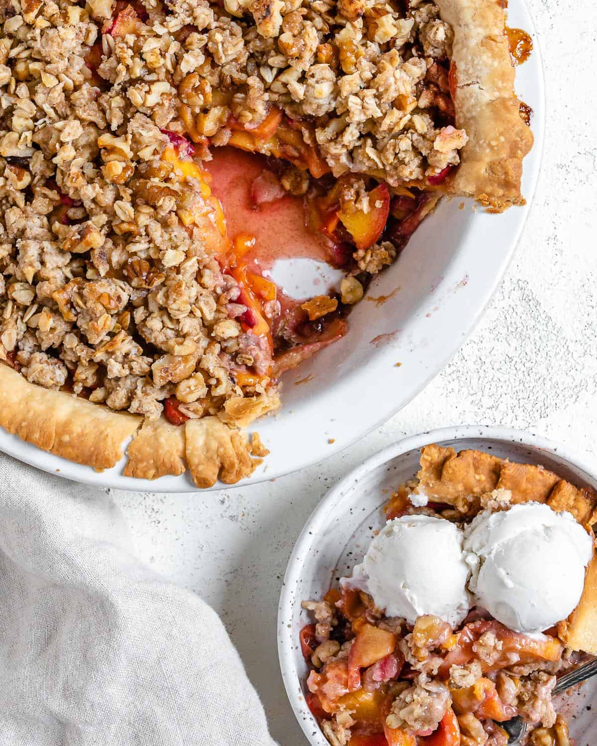 completed Peach Crumb Pie with a slice in a separate white bowl