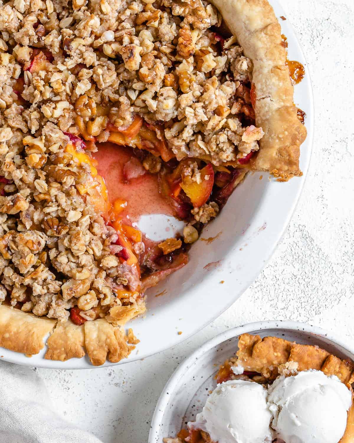 completed Peach Crumb Pie with a slice in a separate white bowl