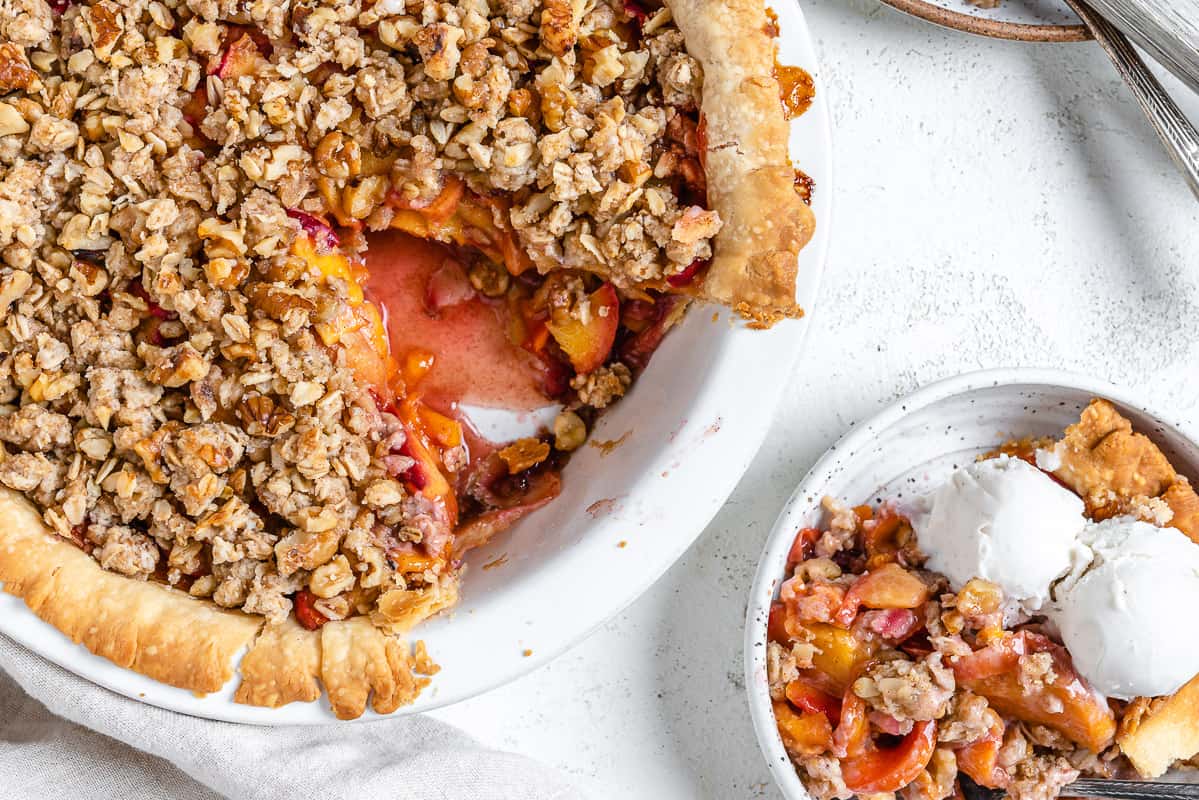 completed Peach Crumb Pie with a slice in a separate white bowl