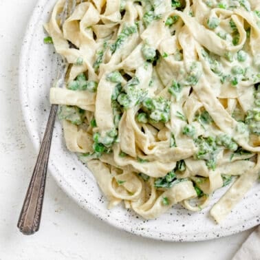 completed Dairy Free Alfredo Sauce with Kale and Peas plated on a white plate against a white surface