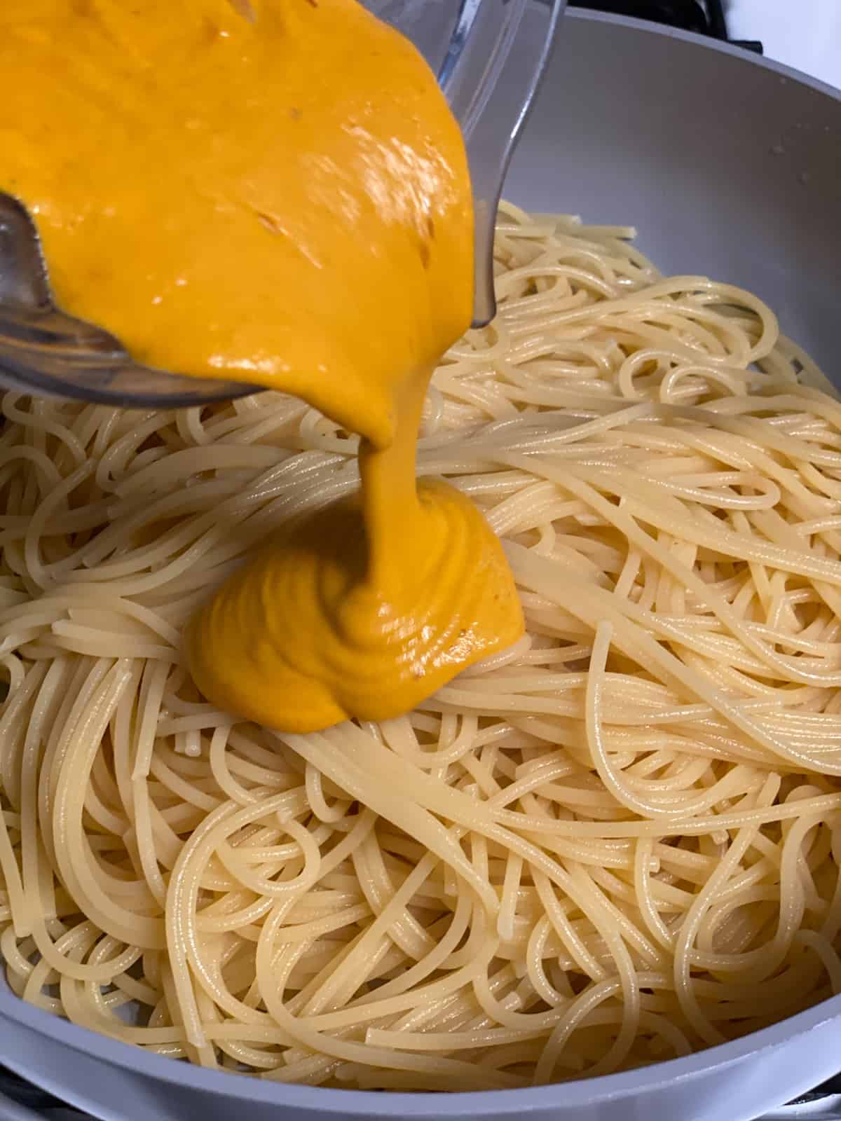 process of adding sauce ingredients to pasta