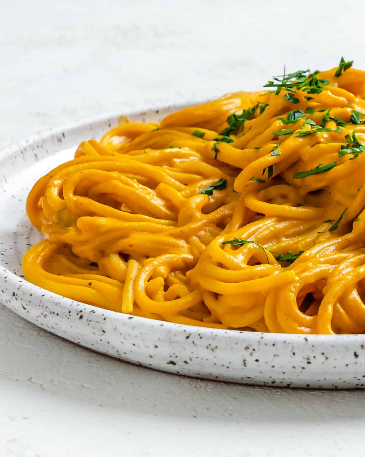 completed Sweet Potato Pasta Sauce with Spaghetti plated against a white surface