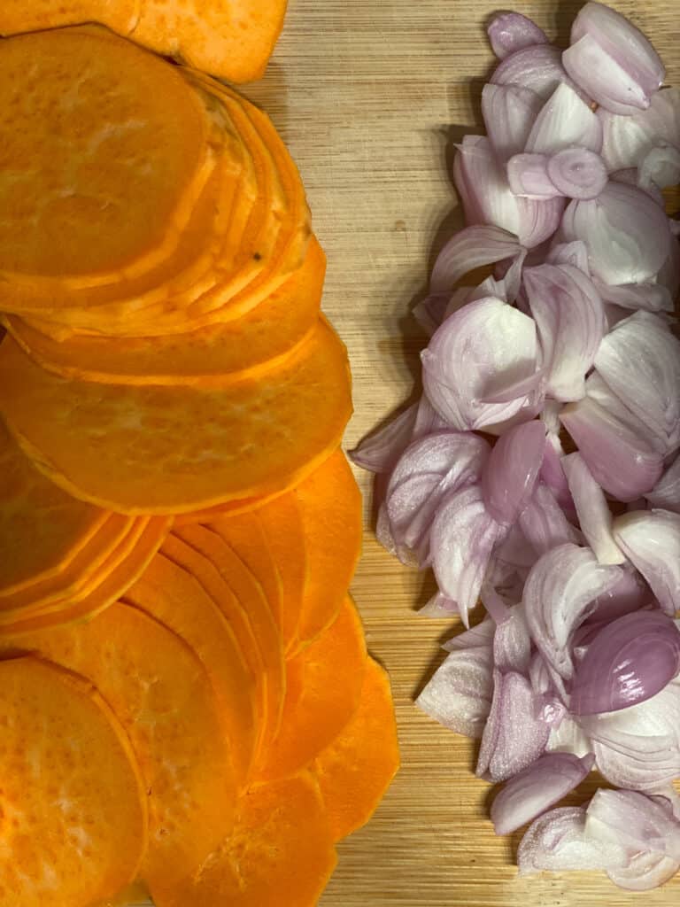close up of sweet potatoes and onions on cutting board
