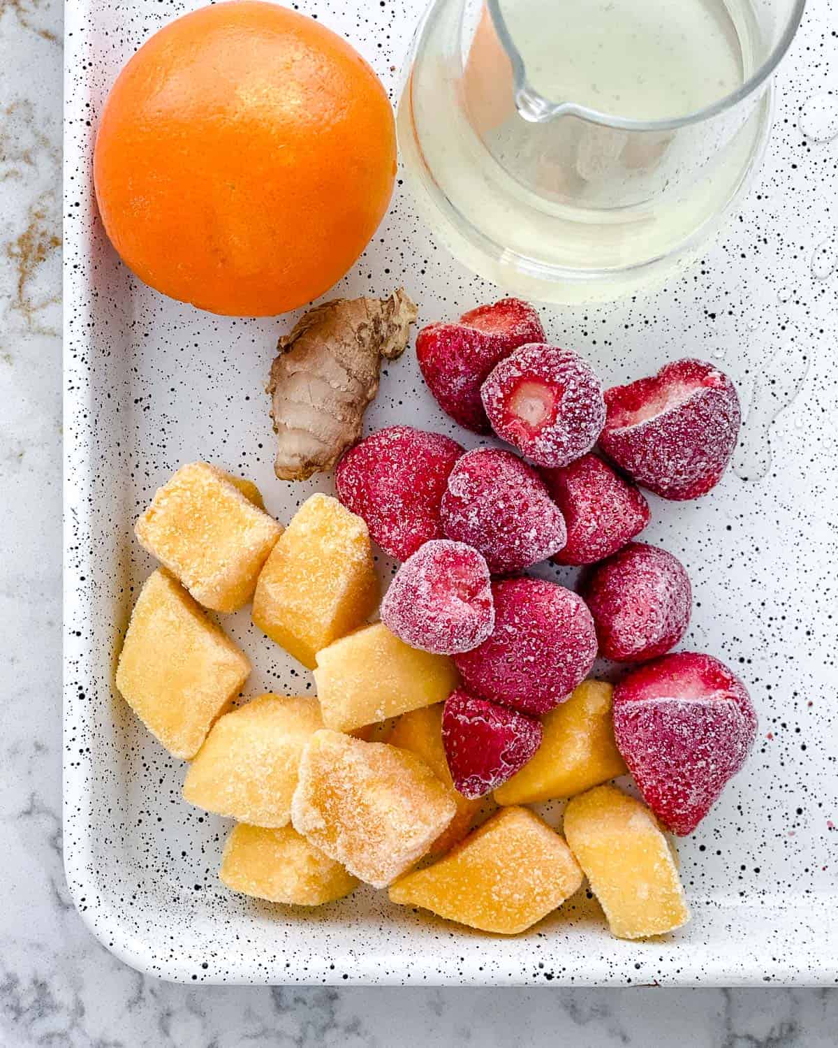 ingredients for ginger fruit smoothie on a white speckled tray