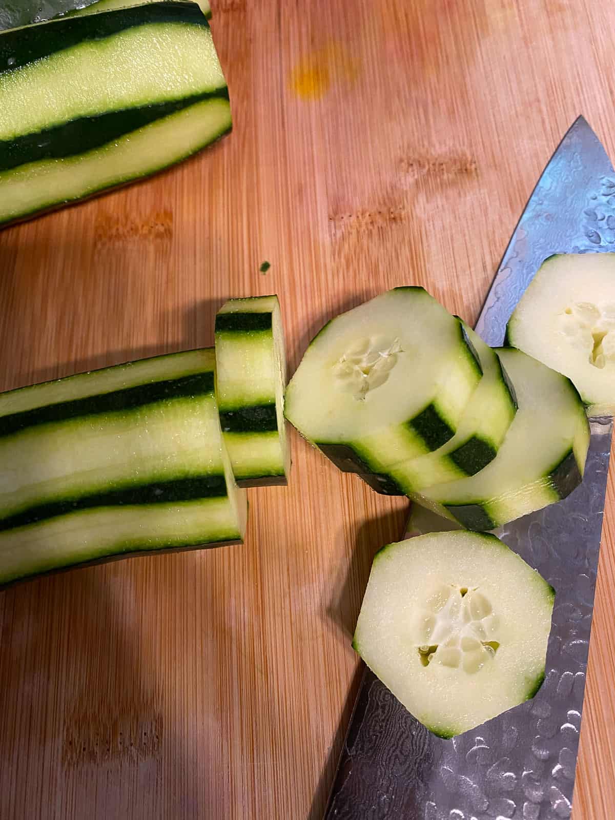 process shot of slicing cucumbers on cutting board