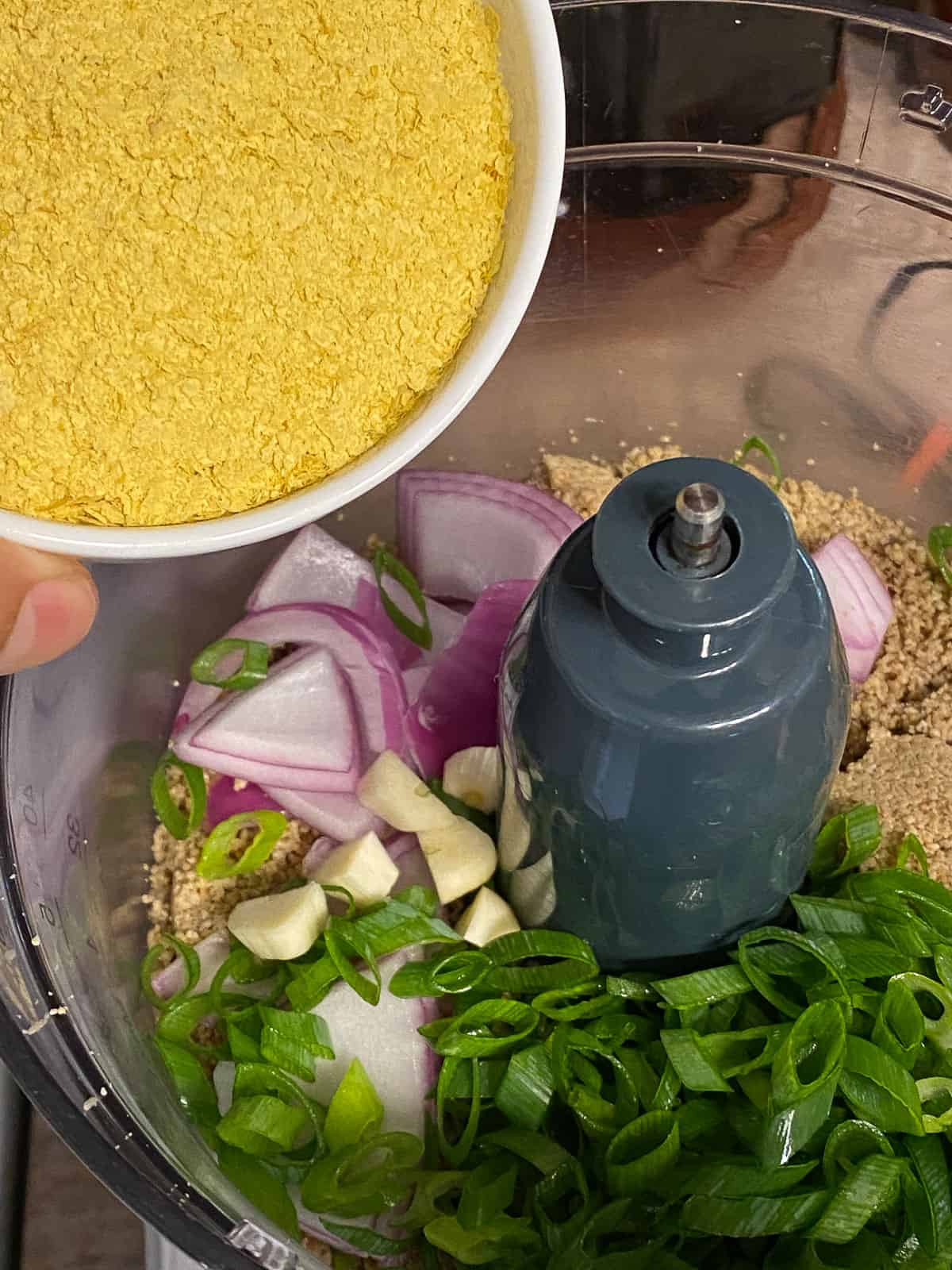 process shot of nutritional yeast being added to food processor