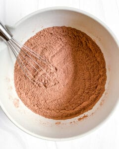 process of mixing Super Fudgy Vegan Brownies ingredients in a white bowl