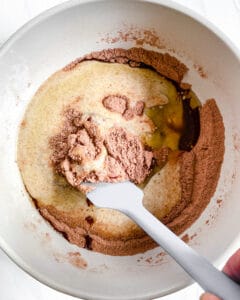 process of mixing the wet ingredients of Super Fudgy Vegan Brownies in a bowl