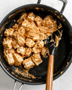 process shot of mixing tofu with sauce in black pan