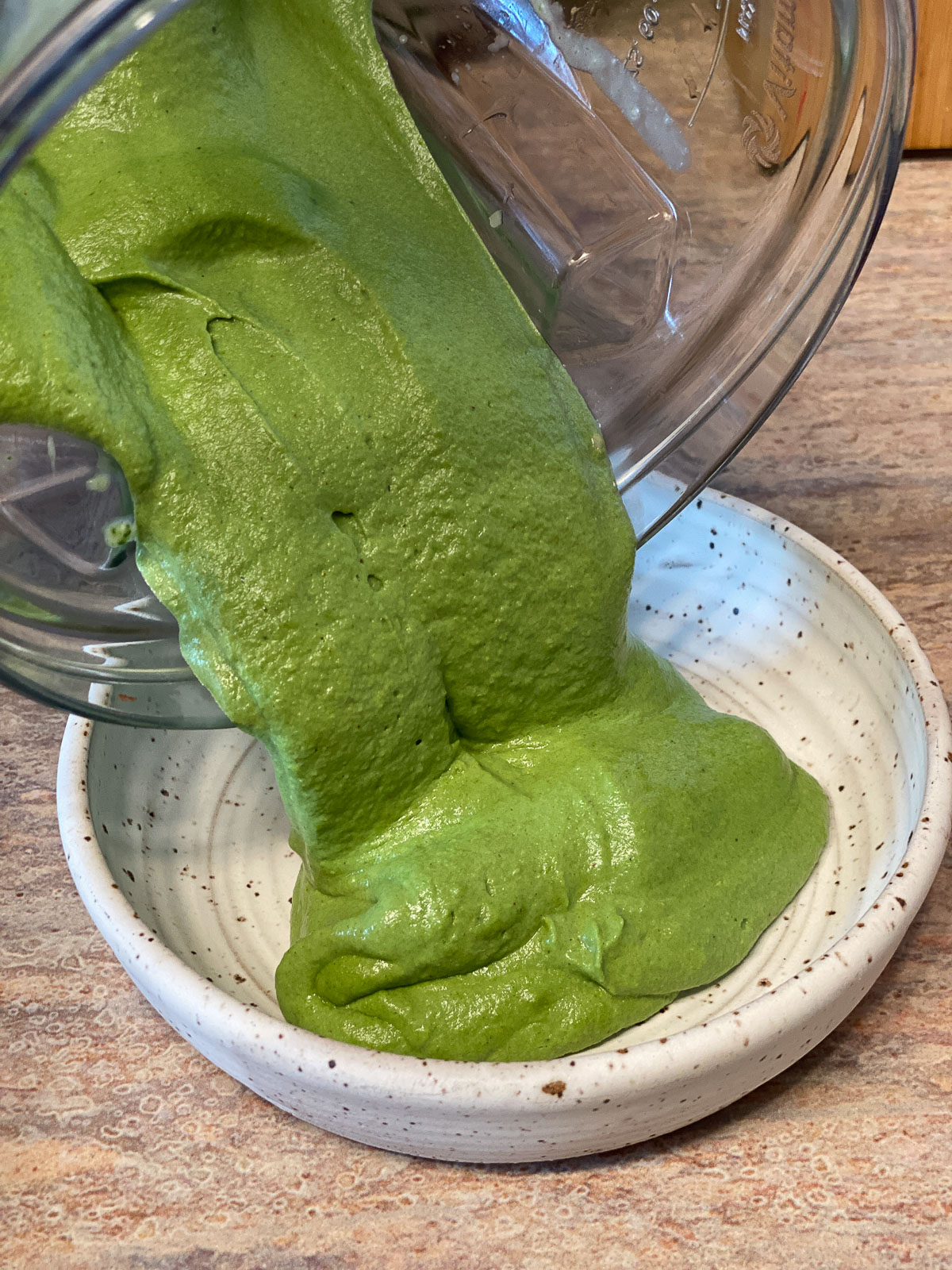 process of pouring spinach dip from blender to bowl