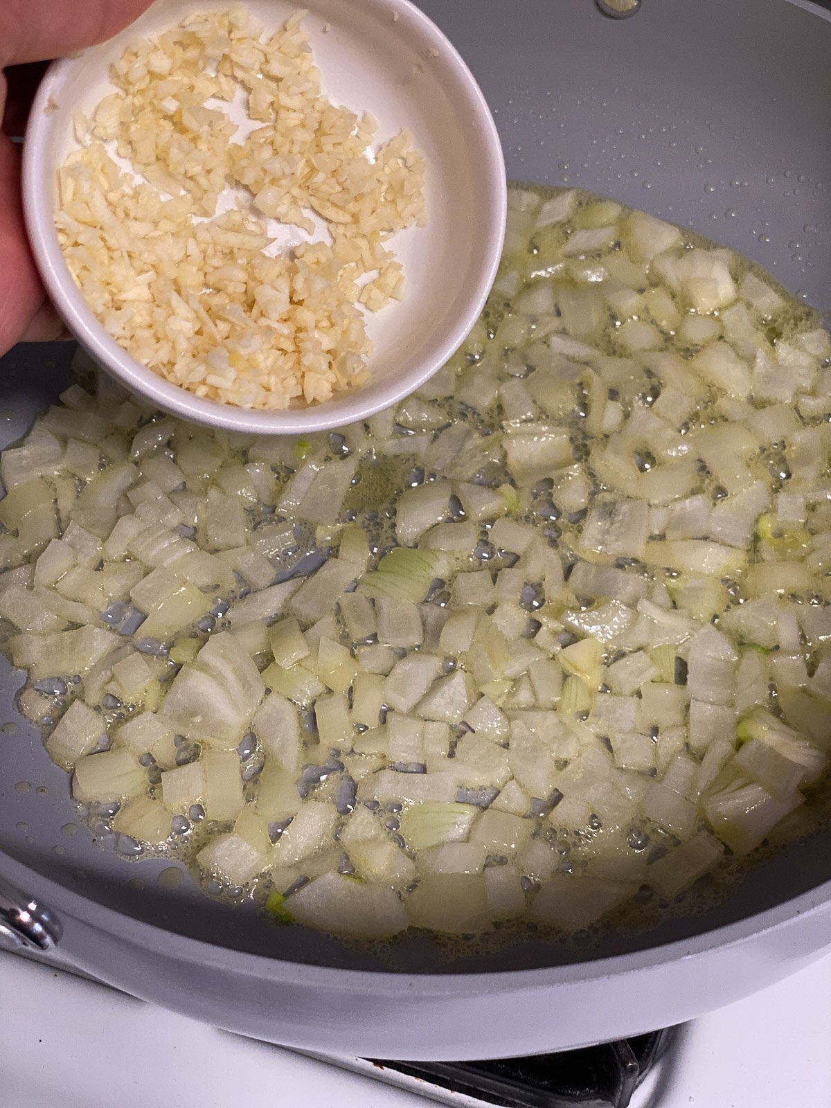 process shot of minced garlic being added to pan