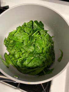 process shot of spinach being cooked in pan