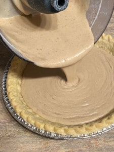 process shot of pouring Vegan Banana Cream Pie ingredients into pie crust