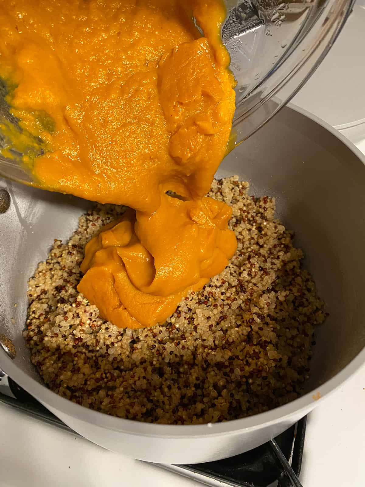 process shot of butternut squash being added to pan of quinoa