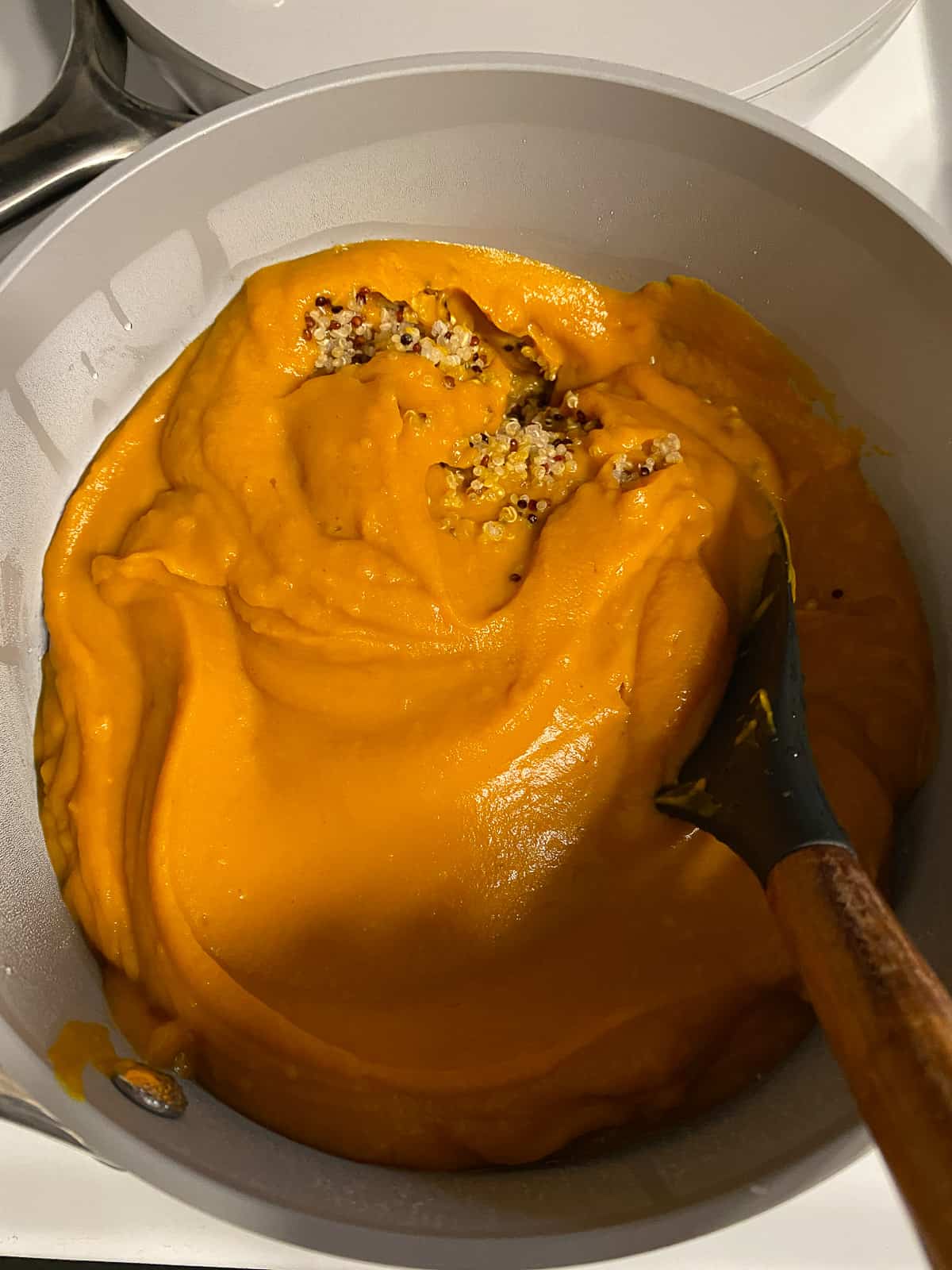 process shot of mixing butternut squash mixture and quinoa in pan