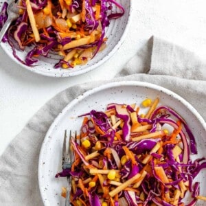 completed vegan slaw on two white plates against a light background