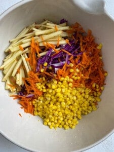 process of adding veggies for slaw into white bowl