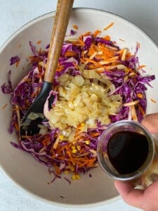 process of adding soy sauce and sugar mixture into bowl of veggies