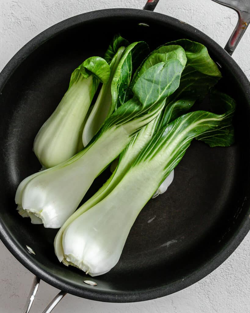 veggies in a black pan against a white background