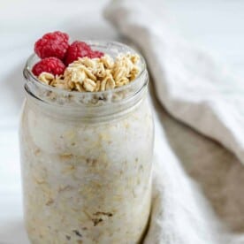 completed jar of coconut overnight oats with granola and fruit topping against a white background