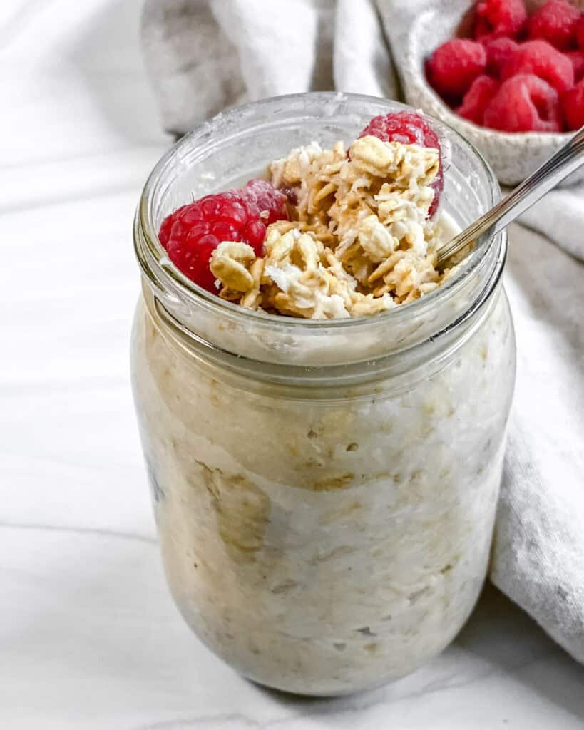 completed jar of coconut overnight oats with granola and fruit topping against a white background