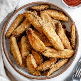 completed oven baked sesame fries on a white plate against a white background