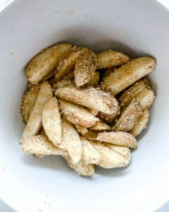 process of mixing seasonings of oven baked sesame fries in a white bowl