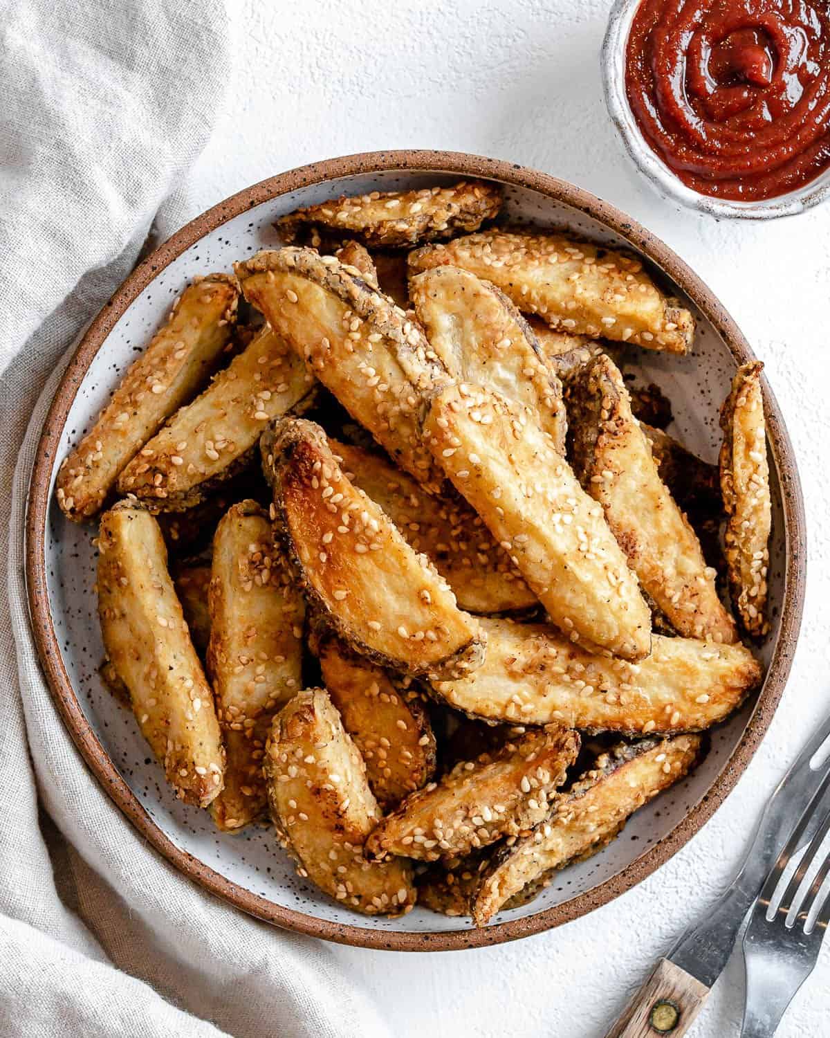completed oven baked sesame fries on a white plate against a white background