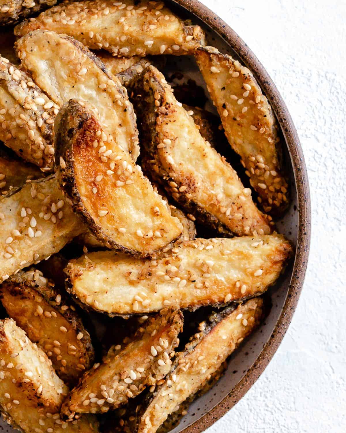 completed oven baked sesame fries on a white plate against a white background