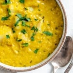 completed Lentil Potato Soup in a white bowl with ingredients in the background