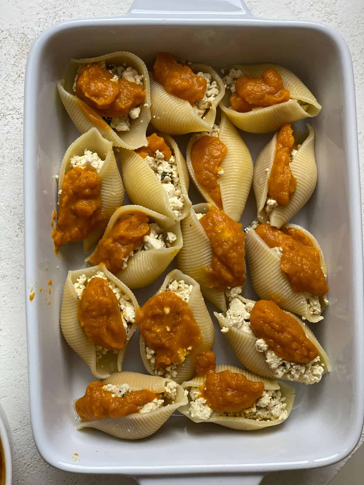 several pumpkin stuffed shells in a baking dish prior to being baked