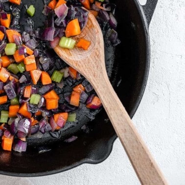 completed mirepoix in a black skilled with a wooden spoon