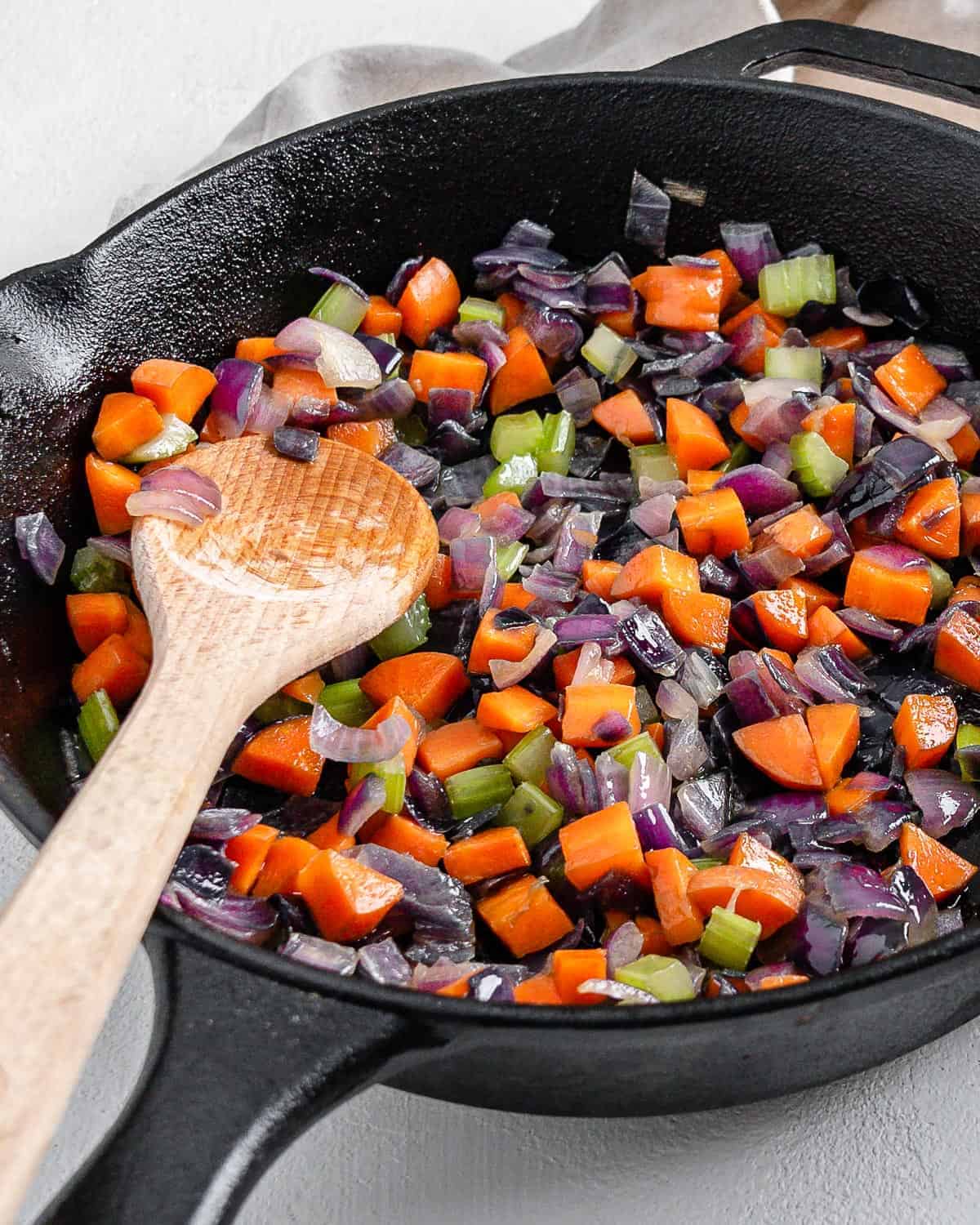 completed mirepoix in a black skilled with a wooden spoon