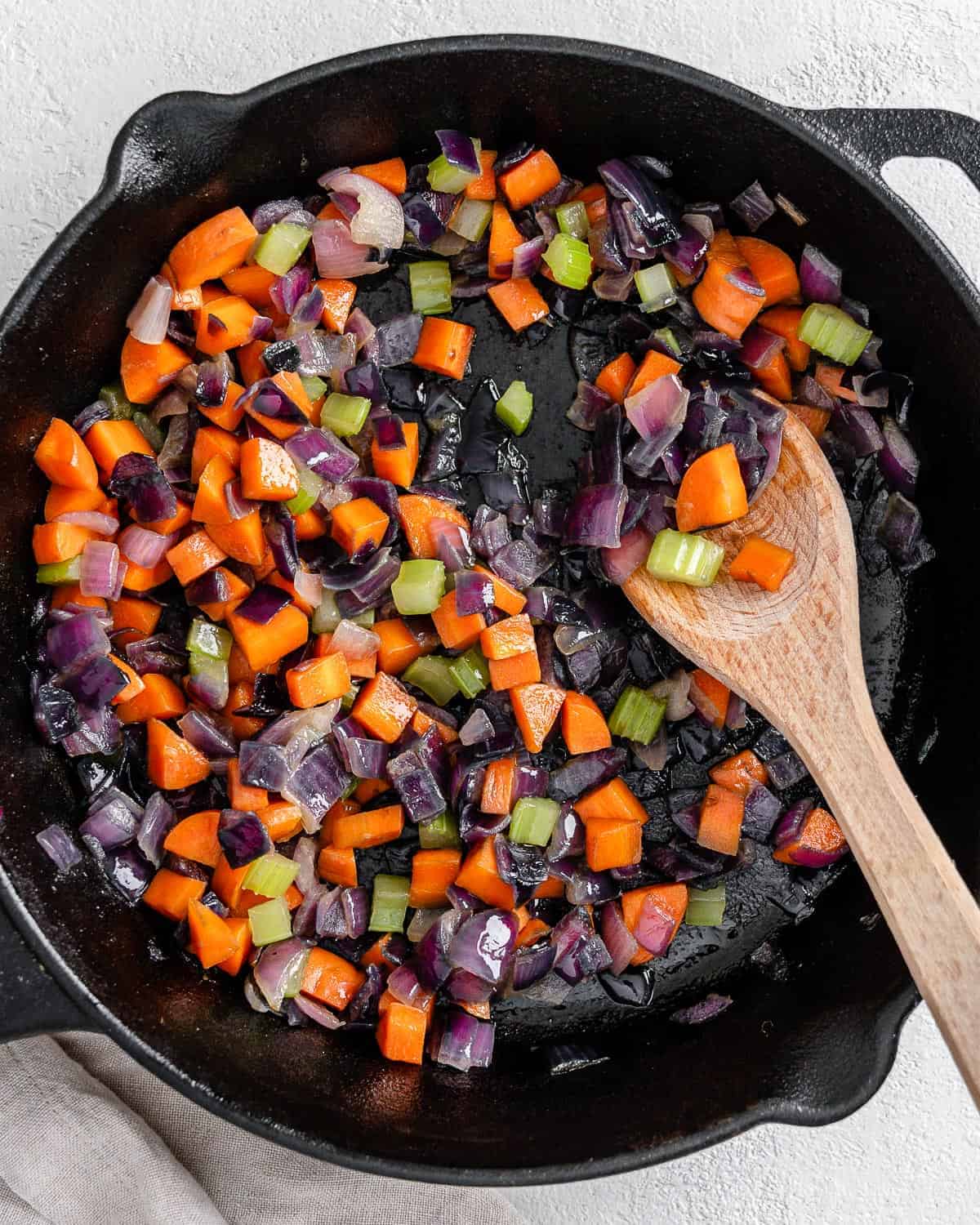 completed mirepoix in a black skilled with a wooden spoon