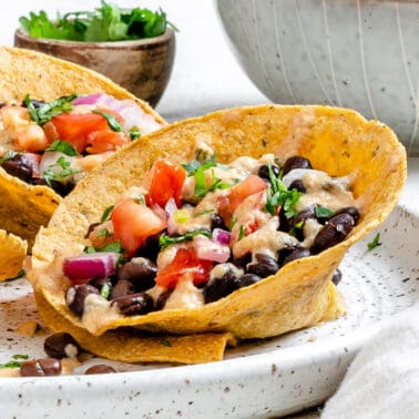 completed Crunchy Taco Cups with Black Beans plated on a white speckled plate